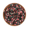 A pile of black and pink floral silicone beads in a wooden bowl for jewelry making