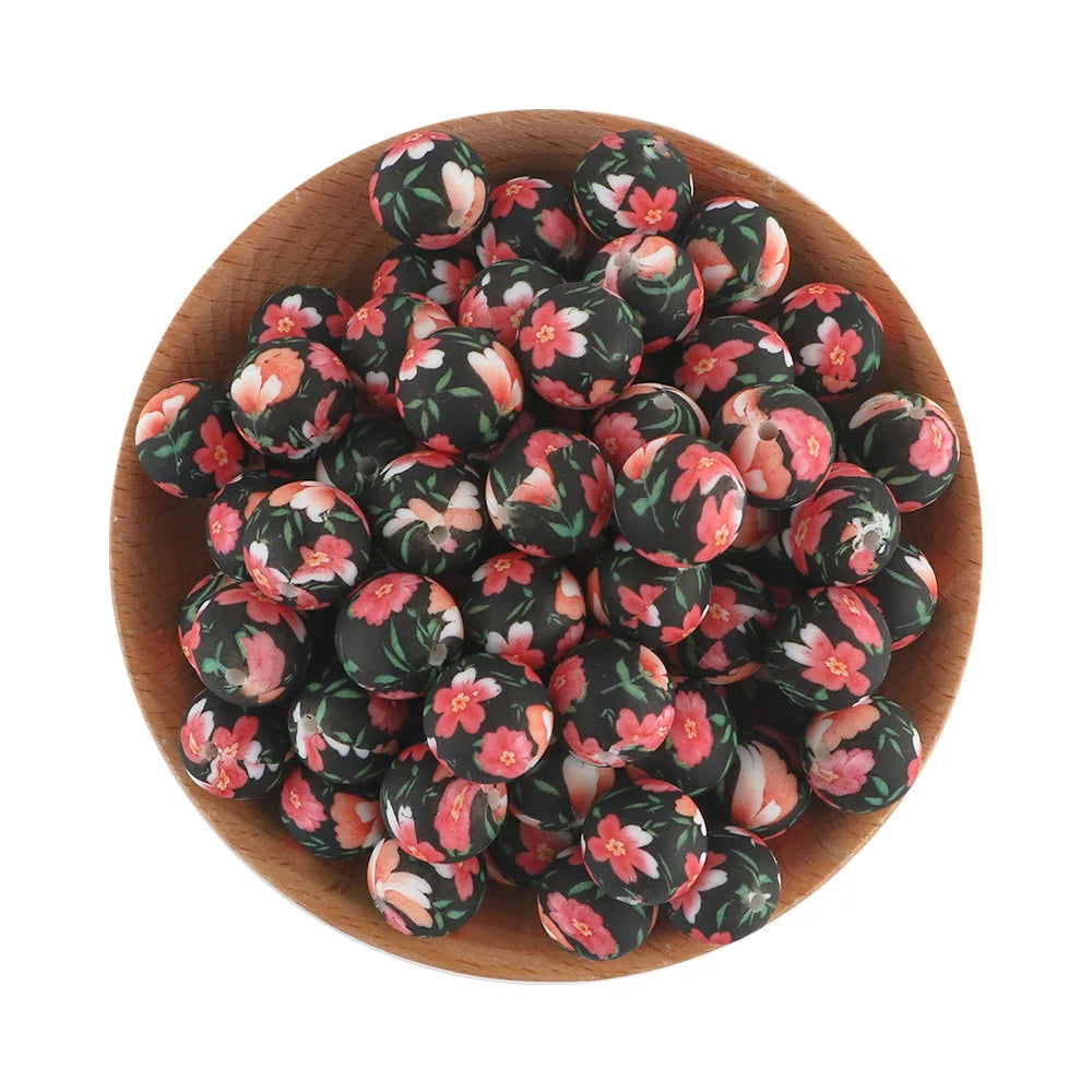 A pile of black and pink floral silicone beads in a wooden bowl for jewelry making