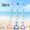Three pull-back water guns in pink, blue, and purple are shown on a sandy beach near the ocean.