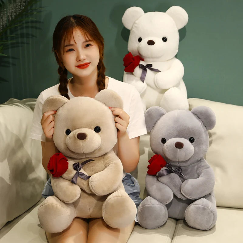 A young woman is holding a pink teddy bear plush toy and standing next to a white teddy bear plush toy.