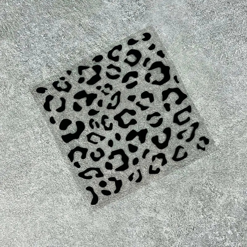 A square decal featuring a black leopard print pattern on a gray surface.