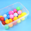 A clear plastic container filled with colorful spherical balls for a party game