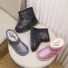 A collection of purple and pink winter snow boots with faux fur lining displayed on a light surface.