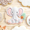 A collection of elephant silicone baking molds in various shades of gray and pink resting on a light wooden surface.
