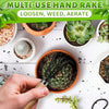 A hand holds a multi-use hand rake tool used for loosening, weeding, and aerating soil around various plants.