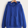 A royal blue oversized zip-up hoodie with a hood and front pocket hanging on a wooden hanger.