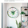 A round analog clock with a green face and colorful markings is displayed on a white wall next to potted plants.