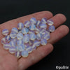 A hand holds a cluster of translucent round beads displaying shades of pink, purple, and white opal stones.