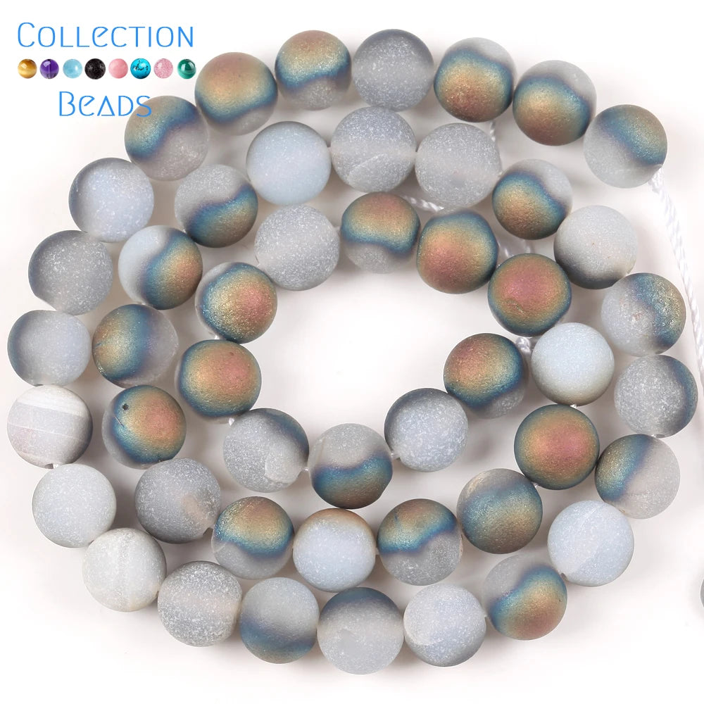 A collection of iridescent beads featuring shades of blue, green, and purple resembling natural sea sediment and turquoise fo