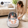 A woman is sitting on the floor with a portable foldable baby bed for supervised rest time placed in front of her.