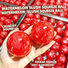 A hand holds a bright red watermelon slush squeeze ball against a background of many similar balls.