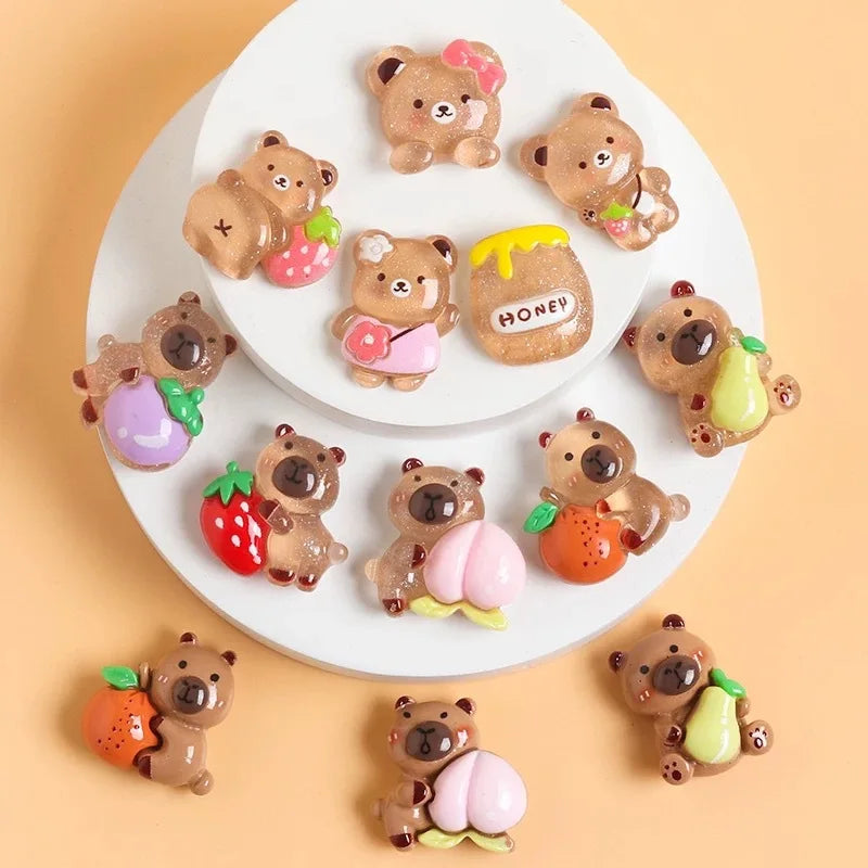 A collection of small resin figurines depicting capybaras holding various fruits and honey on a white plate.