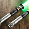 Accessoire effet lightsaber avec lame verte luminescente posé sur une surface en bois à côté d'un smartphone.