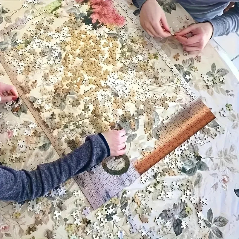 Hands assembling a nautical ship puzzle on a table.