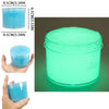 A clear jar of glow-in-the-dark crystal slime with a bright cyan glow, shown next to a hand for scale.