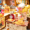 A miniature dollhouse kit featuring a cozy baking kitchen setup with various tools and food items.