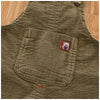 A close-up of olive green corduroy baby cotton overalls with a patch featuring a white bear.