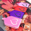 A collection of plastic storage trays in pink, red, and purple are displayed on a diamond painting fabric.