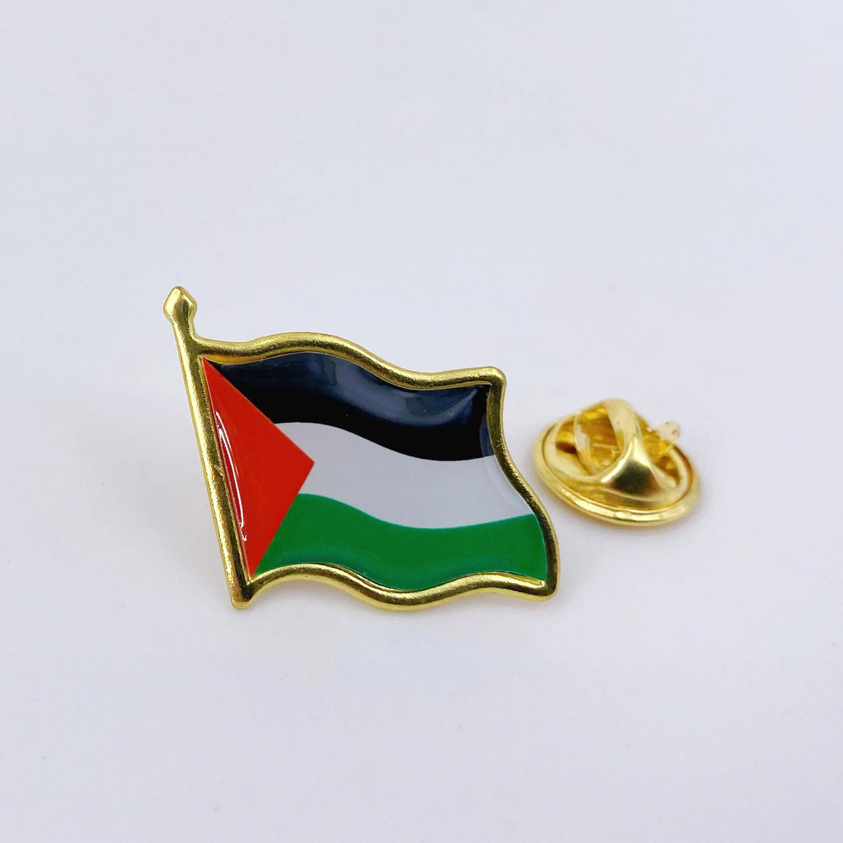 A gold lapel pin shaped like the flag of Palestine featuring black, white, and green stripes.