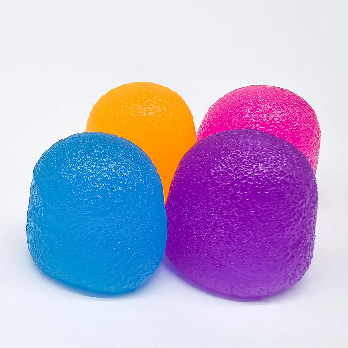 Three brightly colored soft squishy stress relief balls in orange, pink, and blue.