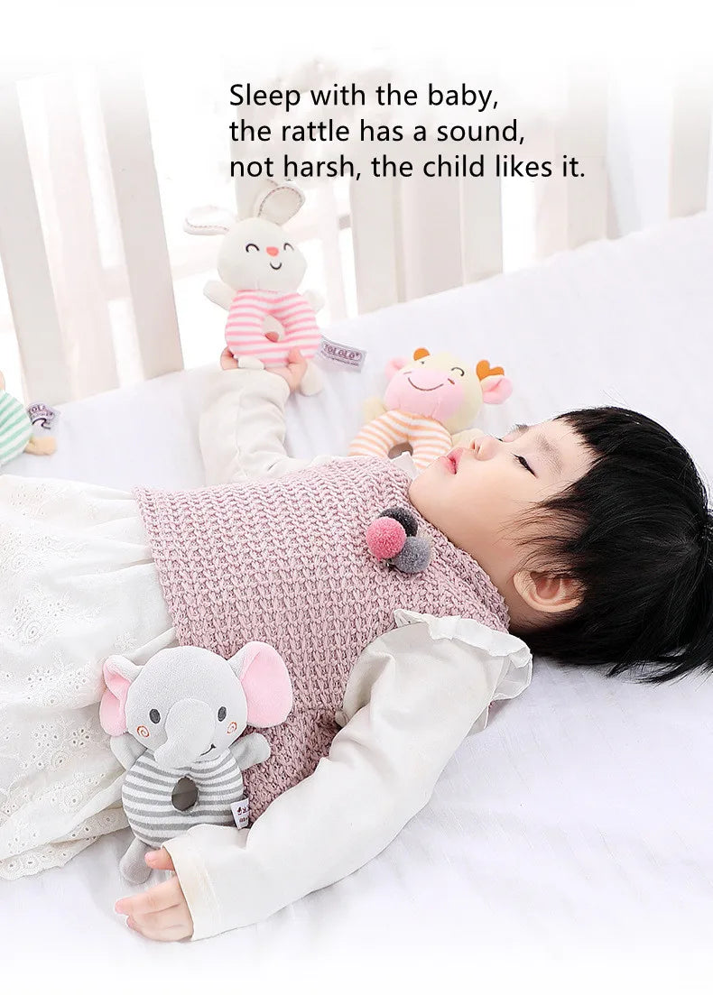 Un bébé est allongé et profite d'un jouet de rattle animal en tricot rose et doux.
