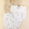 A set of three white muslin baby bibs with ruffled edges and small floral embroidery displayed on a light background.