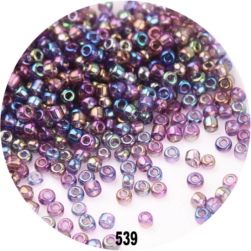 A close-up view of loose, colorful round Czech glass seed beads in various shades of purple and blue.