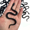 A hand is holding a realistic soft rubber black snake prop.