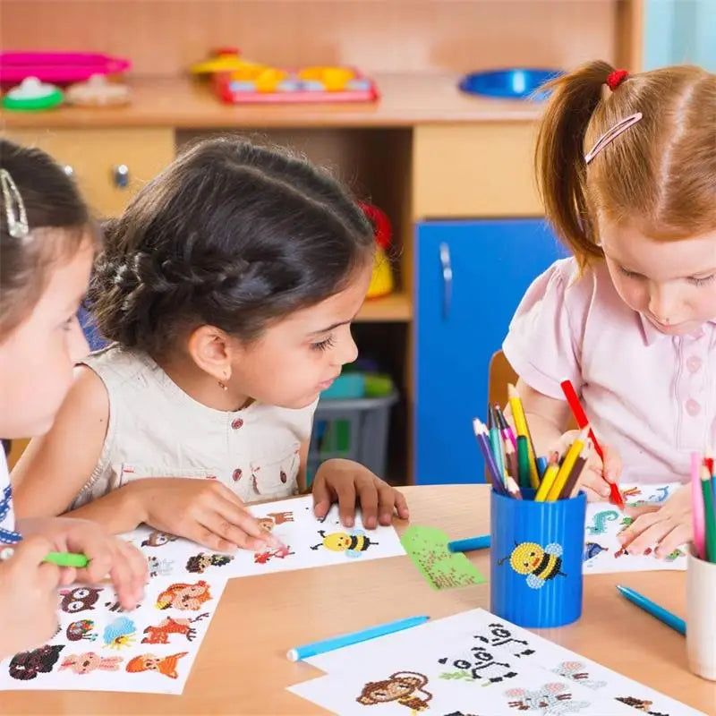Two young girls are painting on paper with a sparkling diamond painting sticker kit featuring floral and butterfly designs.