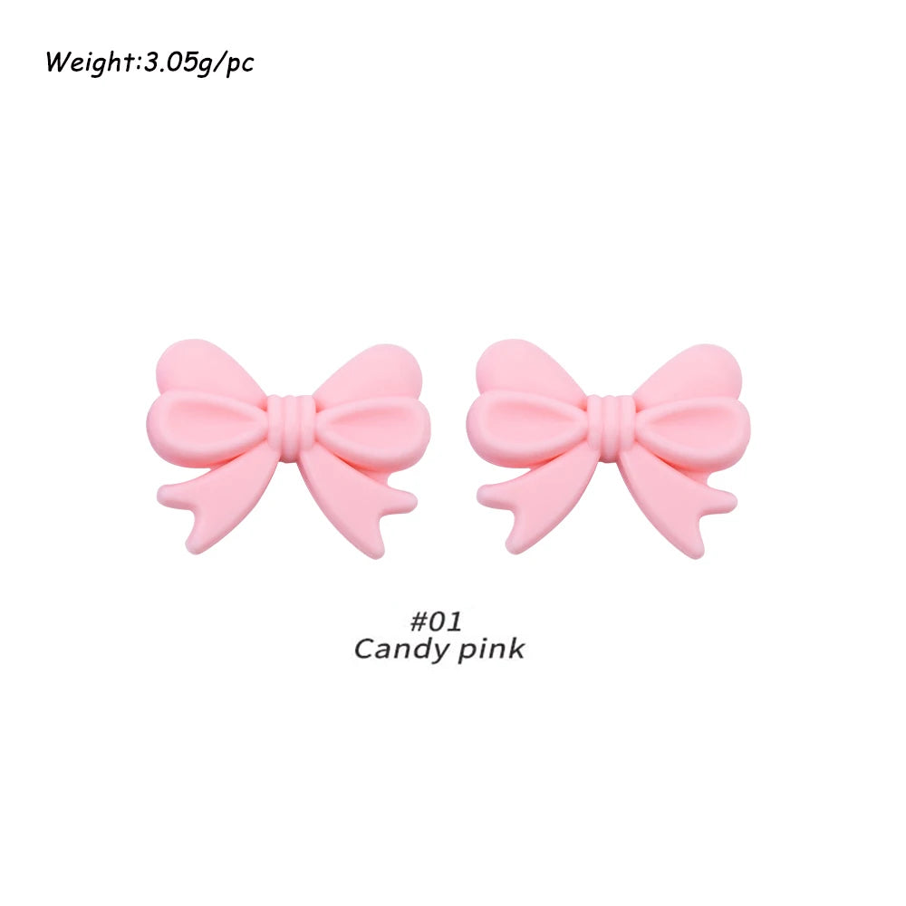 A pair of pink silicone bow tie beads used for jewelry making and craft projects.