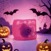 A pink squishy toy shaped like a ghost with white snowflake details is displayed in front of carved pumpkins.