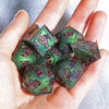 A hand holds a set of handmade resin polyhedral dice in various colors and angles.