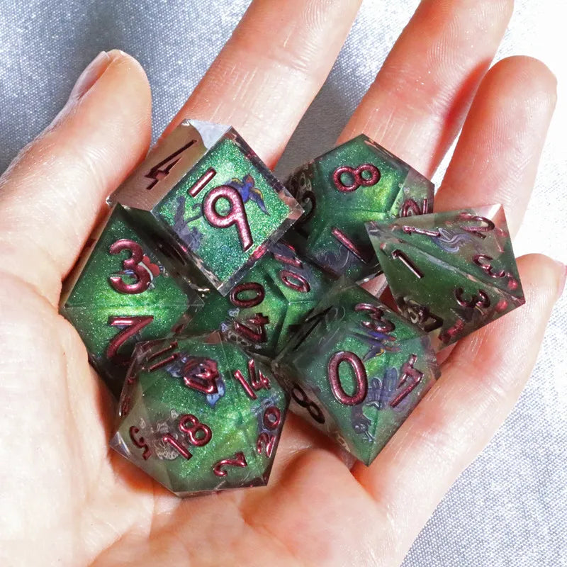 A hand holds a set of handmade resin polyhedral dice in various colors and angles.
