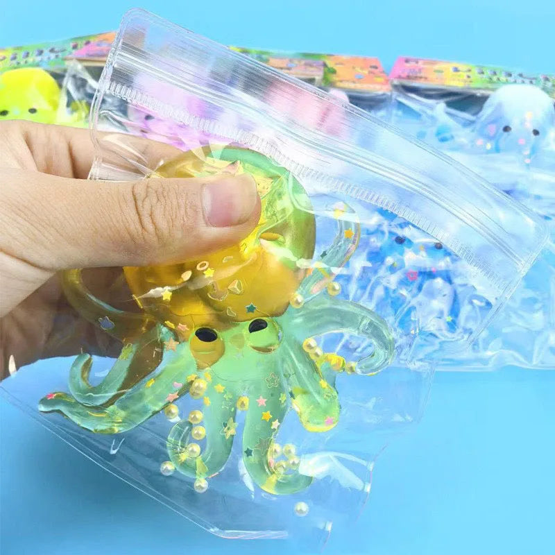 A hand holds a translucent yellow and green ocean octopus squishy toy packaged in clear plastic.