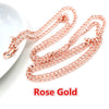 A delicate rose gold chain necklace laid out on a white surface.