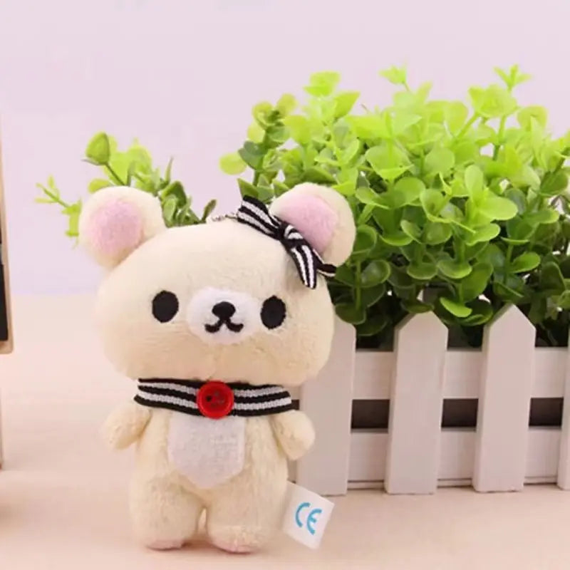 A fluffy white bear plush toy with pink ears and a black bow, standing in front of a green plant.