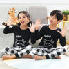 Two children wearing black long-sleeved shirts and checkered pants posing indoors.