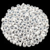 A pile of small white acrylic alphabet letter beads in various shapes and sizes.