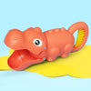 An orange plastic dinosaur toy with a yellow claw and digging tools lying on a light blue surface.