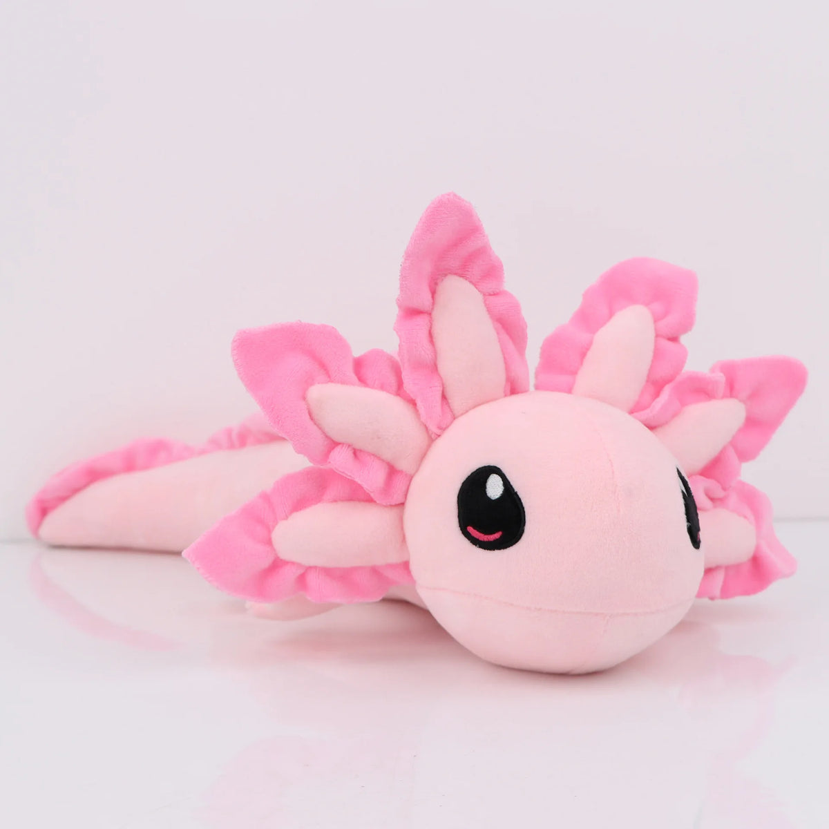 A pink plush toy of an axolotl with large ears and a smiling face.