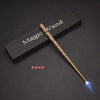 A golden magic wand with an LED light tip rests on a dark surface next to a wooden box labeled Magic Wand.