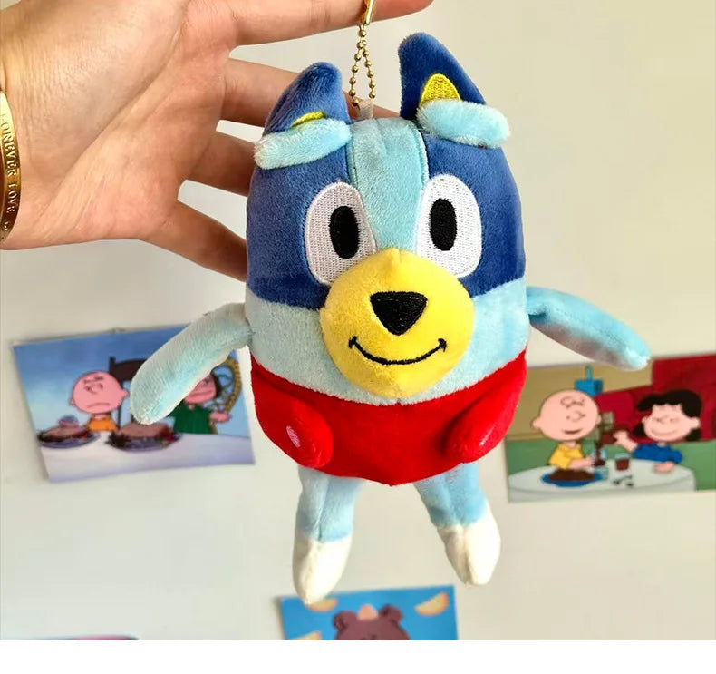 A blue and white plush toy of a dog character, resembling Bluey, being held by a hand.