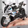 A white and black 1:12 scale die-cast model motorcycle with front steering is shown resting on a hand.