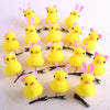 A collection of yellow duck plush hair clips with pink ears arranged on a white background.