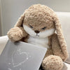 A light brown angry rabbit plush doll with white accents sitting on a white surface.