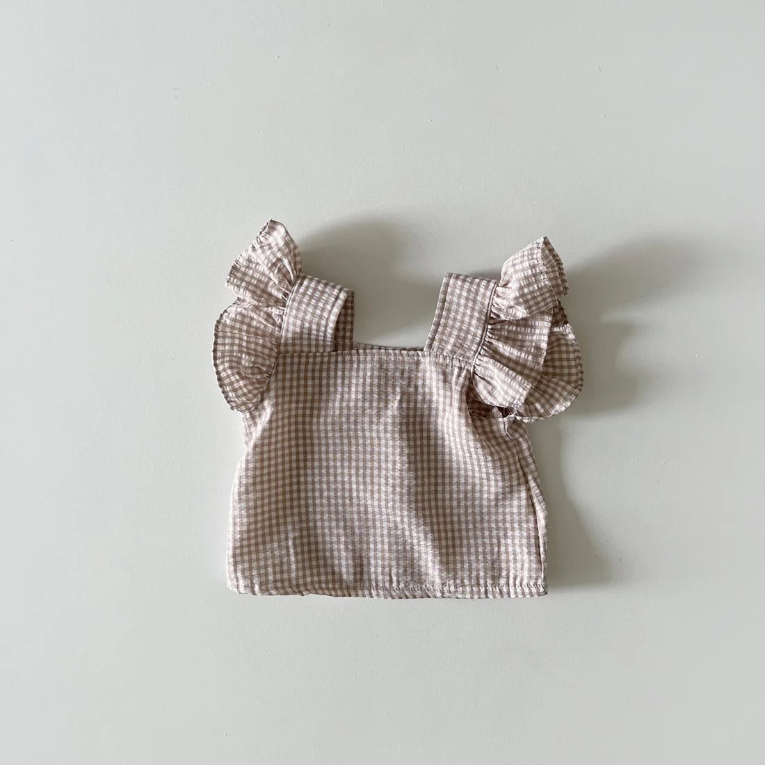 A light pink gingham ruffle top and shorts set for a baby girl summer outfit.