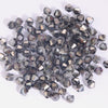 A pile of faceted crystal bicone glass beads in various shades of gray and clear, used for jewelry making.
