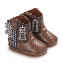 A pair of brown baby western booties with white leaf embroidery and a soft non-slip sole.