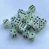 A pile of ten glow-in-the-dark dice in a pale green color scattered on a white surface.