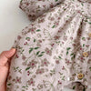 Close-up of a beige floral print baby girl long sleeve jumpsuit fabric with small embroidered flowers.